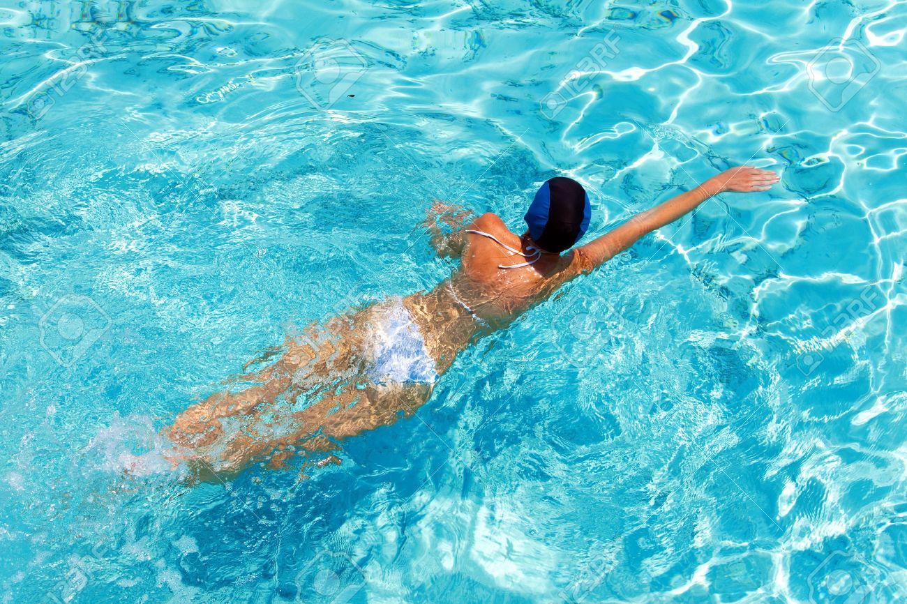 Девушка в бассейне плавает со спины